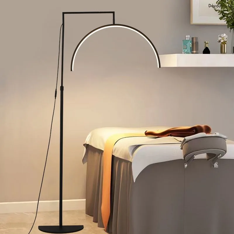 Floor-standing beauty lamp in black, lit over a treatment bed